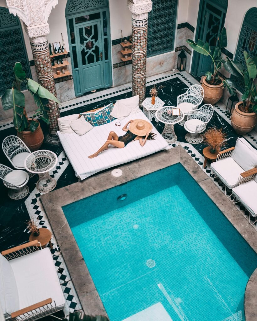 pexels-photo-3889843-3889843 Elegant indoor pool with a woman lounging, set within a Moroccan riad in Marrakesh.