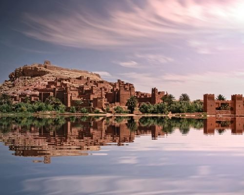 pexels-photo-3581916-3581916 Picturesque reflection of Ouarzazate's historic ksar by the river under a vibrant sky.